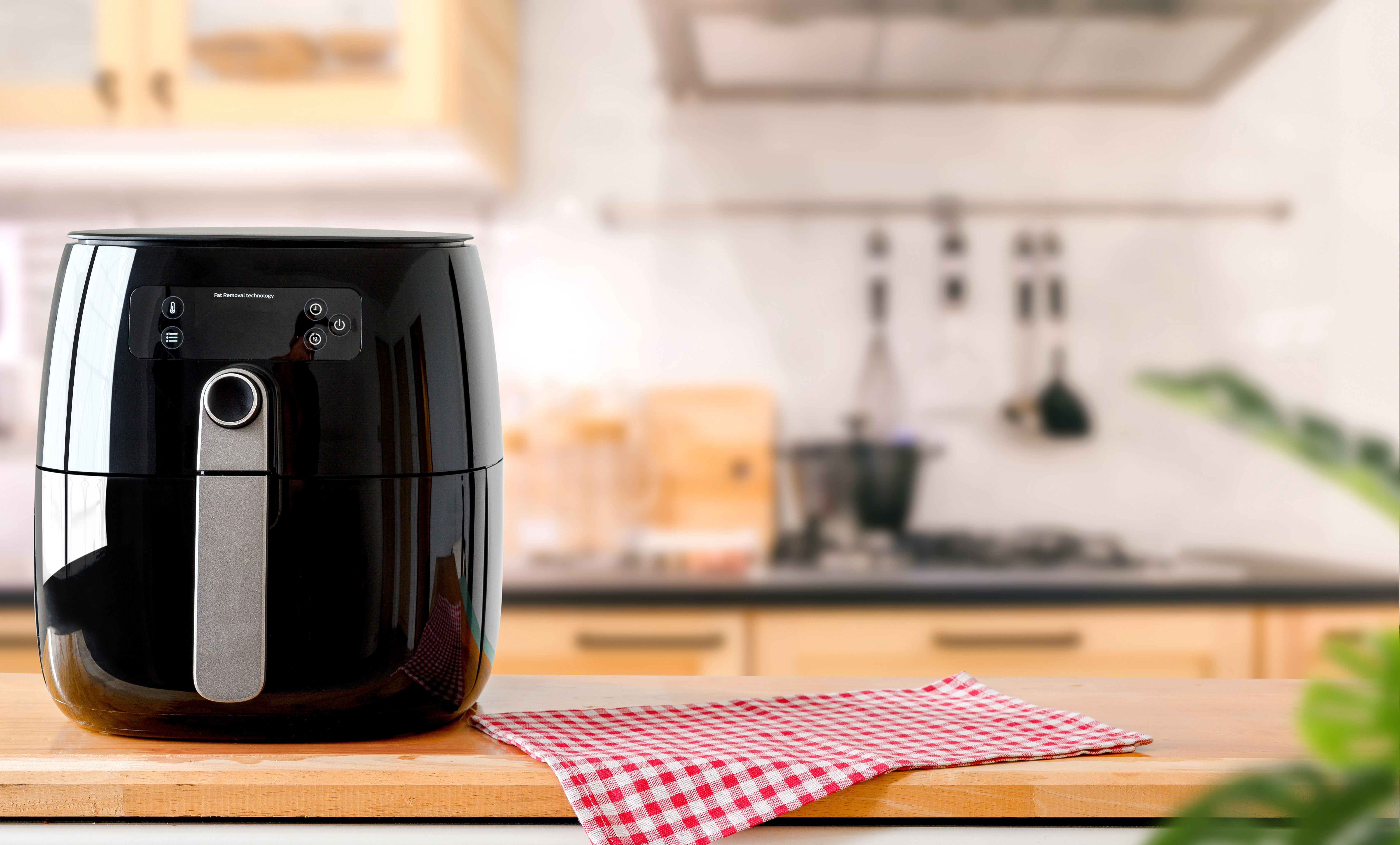 An electric Air Fryer on table with blurred kitchen background An electric Air Fryer on table with blurred kitchen background