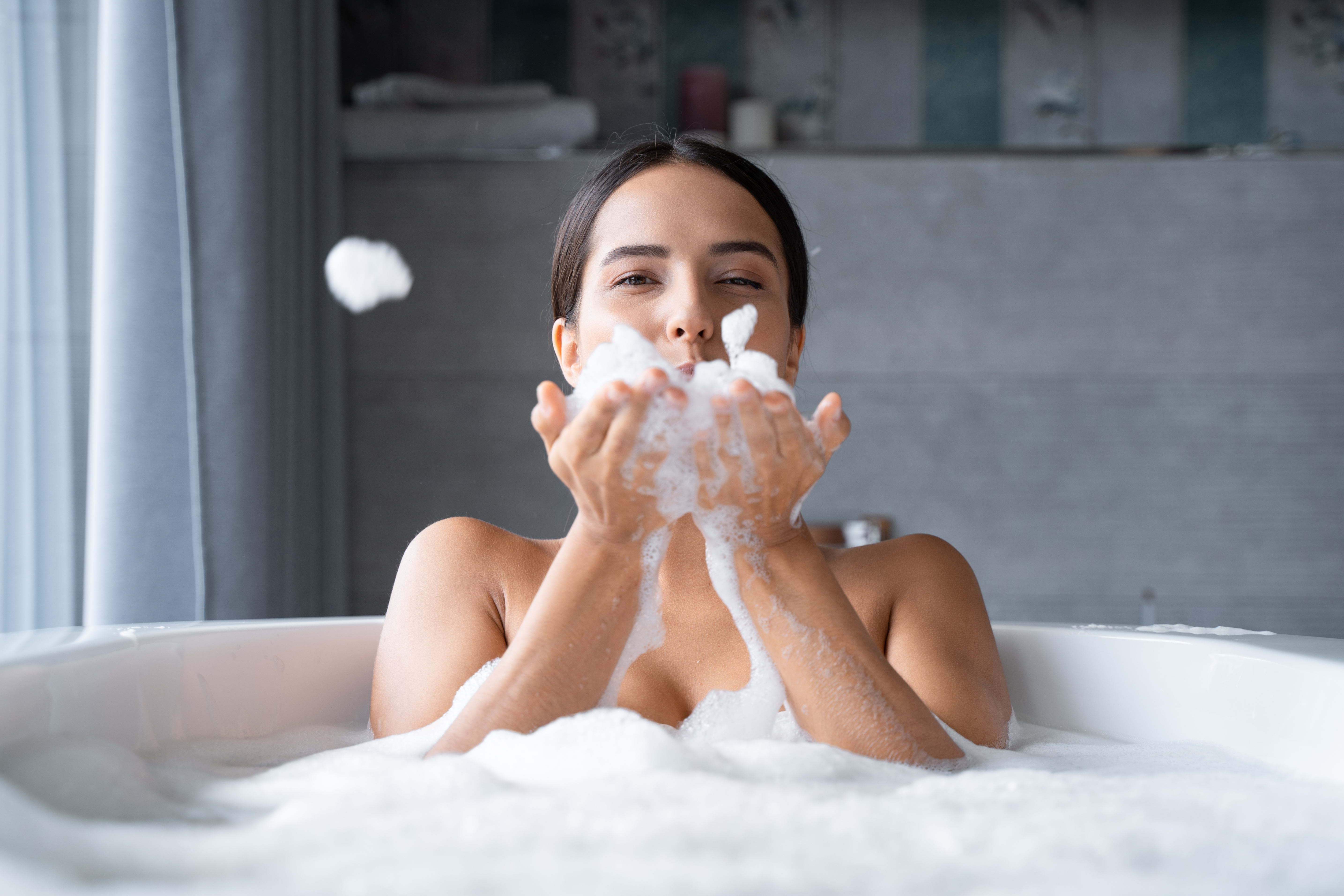 Relaxed young woman sitting in a bathtub with foam Relaxed young woman sitting in a bathtub with foam