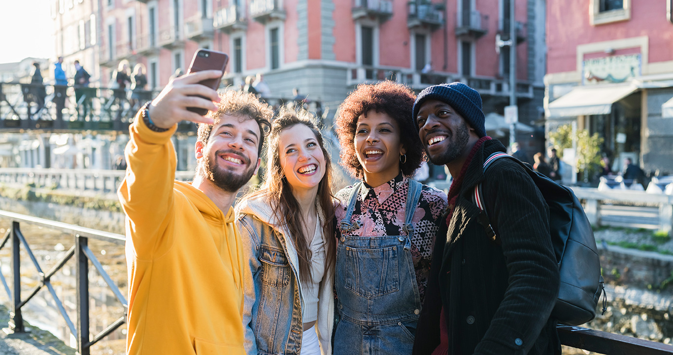 Four female and male young adult friends taking selfie on city canal waterfront Four female and male young adult friends taking selfie on city canal waterfront