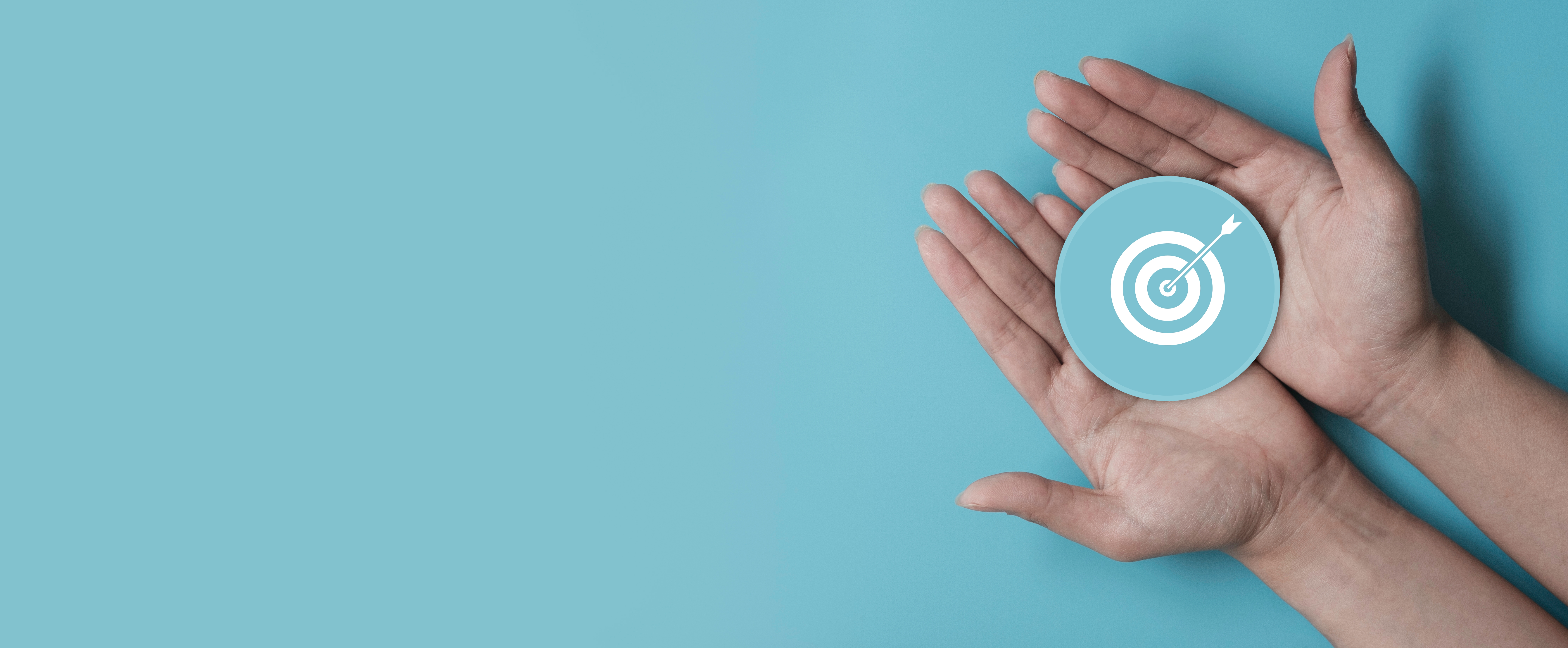 Hand holding blue paper cut with target icon Hand holding blue paper cut with target icon