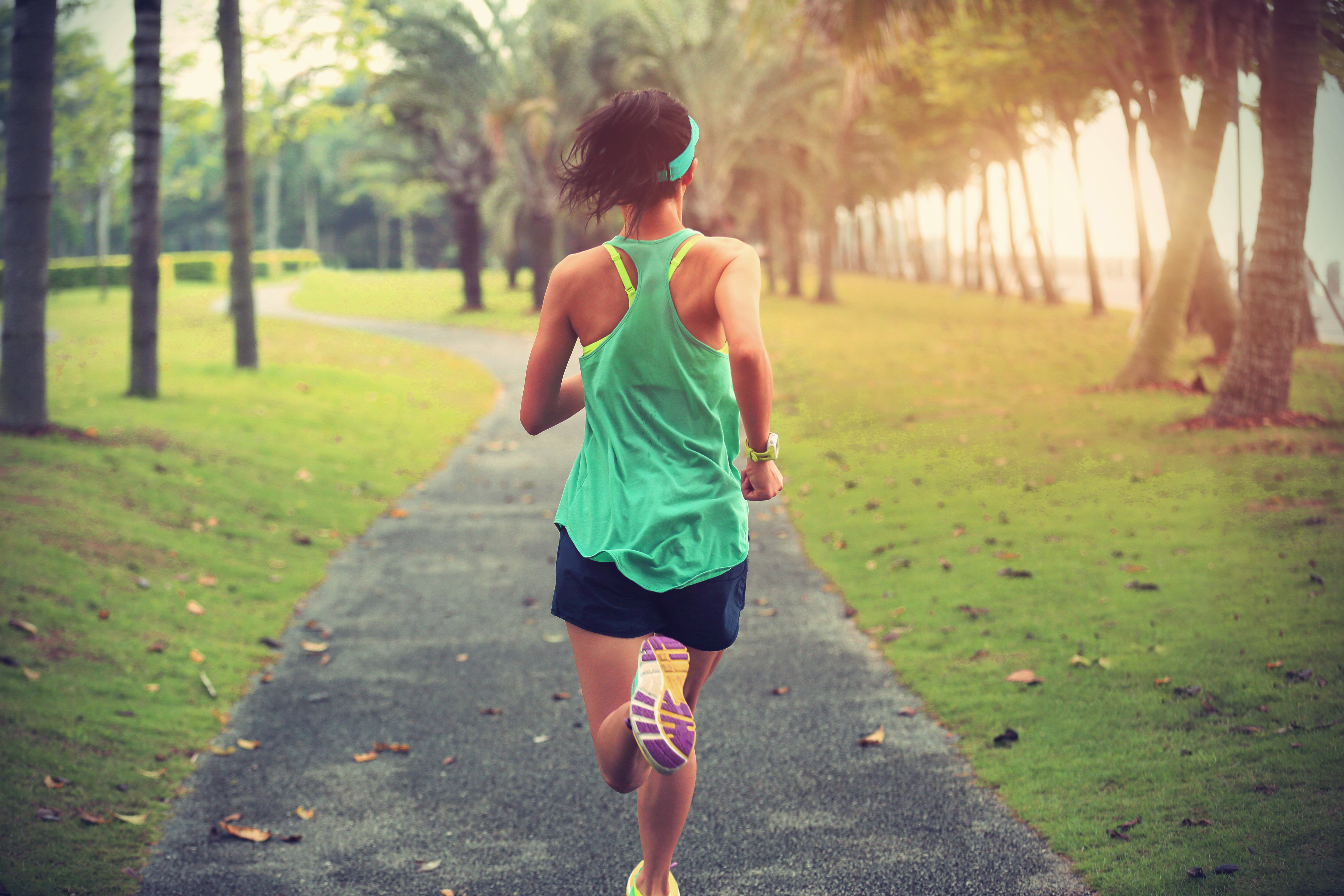 Young fitness sportswoman runner running on tropical park trail Young fitness sportswoman runner running on tropical park trail
