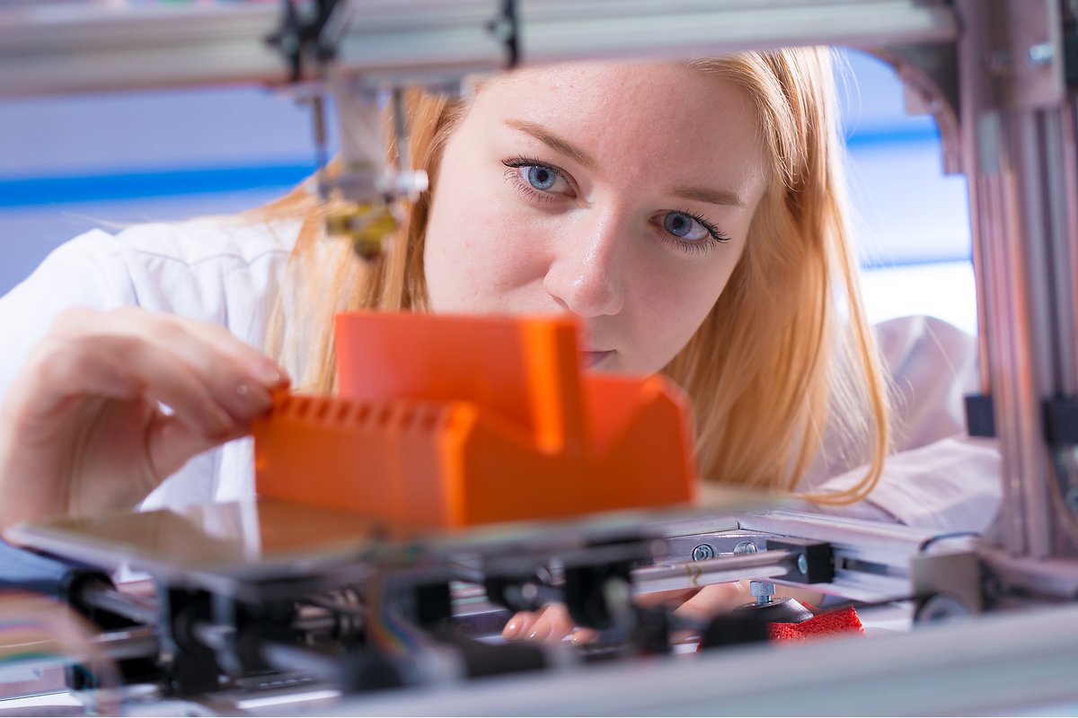Young woman working with 3D printer