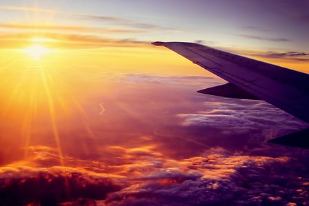 Airplane flying high above the clouds at sunset