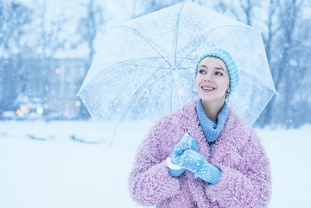 Outdoor portrait of young beautiful happy smiling girl walking in snow-covered street